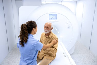 Tıbbi muayene odasında MR çekilirken kıdemli hastaya yardımcı olan kadın doktor..