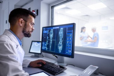MRI tanı merkezi kontrol odası ve nörolog hastanın röntgen görüntülerini büyük ekranda inceliyor..