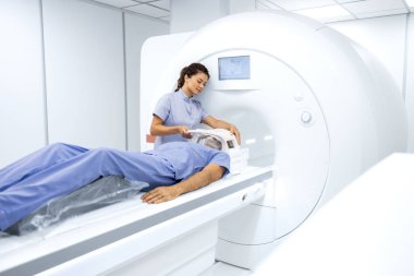 Kadın radyolog ya da teknisyen yaşlı adamı onkoloji teşhis merkezinde MRI ya da CT taramasına hazırlıyor..