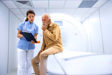 MRI teknisyeni hastayı hastane muayene odasında tarama işlemine hazırlıyor..