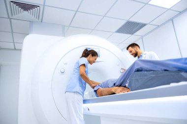 Doktorlar hastayı MRI tanı merkezinde tam vücut tarama prosedürüne hazırlıyorlar..