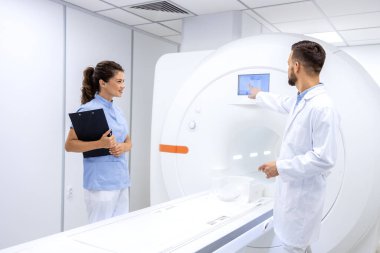 Radyologlar ve doktorlar hastanede modern MRI tarama makinesini kontrol edip hazırlıyorlar..