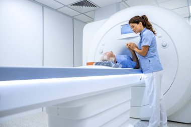 Kadın doktor, hastanede MRI taramasından önce yaşlı hastayı rahat ettiriyor..