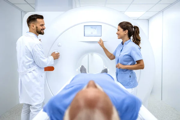 Doctors preparing patient for full body scanning procedure inside MRI diagnostic center.