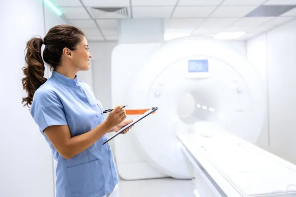 Female radiologist standing inside MRI scanning room.