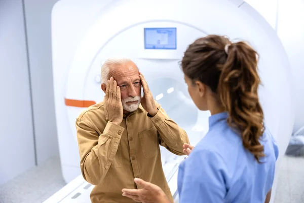 MRI technician preparing patient for scanning procedure in hospital examination room.
