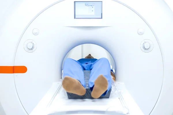 Patient lying inside MRI scanning machine in hospital.