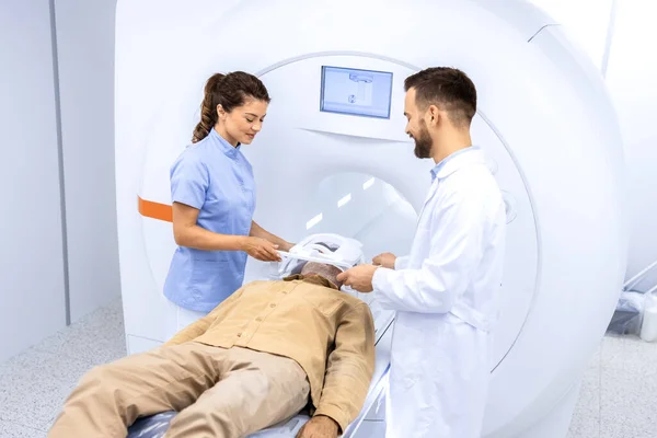 Doctors preparing patient for full body scanning procedure inside MRI diagnostic center.