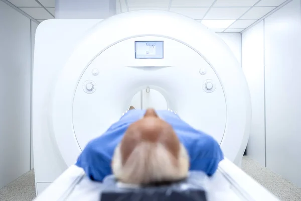 Patient with health problems lying inside MRI scanning machine in hospital.