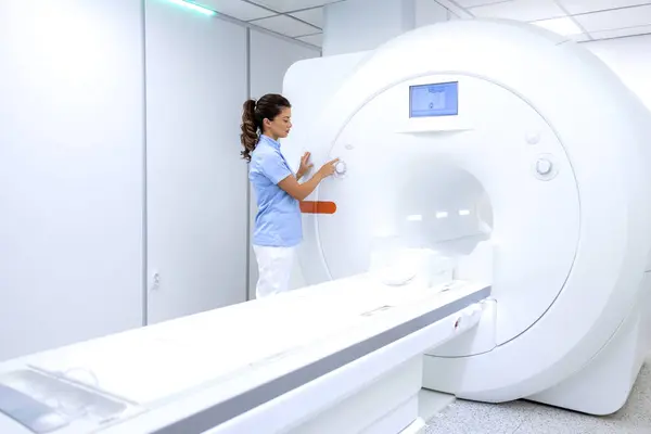 Nurse preparing MRI machine for scanning examination.