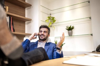 Ofiste akıllı telefon kullanan rahat bir iş adamı..