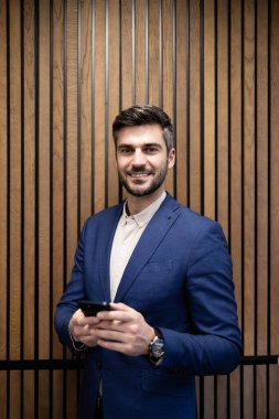 Toplantı odasında akıllı telefon kullanan beyaz takım elbiseli bir müdürün portresi..