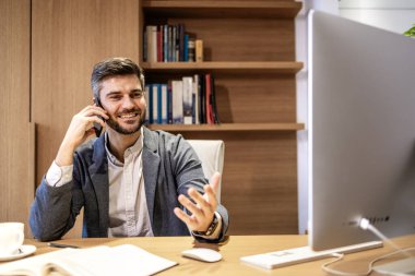 İş adamı telefonda konuşurken bilgisayarına bakıyor ve mali sonuçları okuyor..