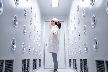 Fabrika işçisi, üretim salonuna girmeden önce özel toz içinde duruyor ve temizlik odasını temizliyor..