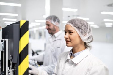 Otomatik üretim makinesinde endüstriyel bilgisayar kullanan fabrika işçileri.