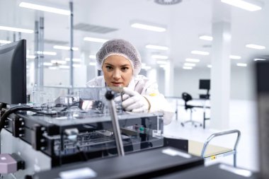 Araba montaj endüstrisinde çalışan kadın uzman ya da teknoloji uzmanı elektronik parçalar üretiyor..