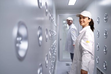 Fabrika işçisi endüstriyel hava üfleme tünelinde duruyor. Üretim hattına girmeden önce toz ve parçacıkları temizliyor..