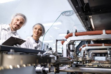 Bir grup bakım mühendisi yüksek teknoloji fabrikasında duruyor ve endüstriyel makinelere hizmet veriyor..