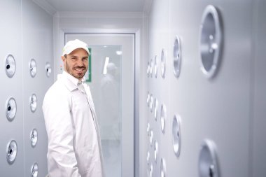 Fabrika işçisi endüstriyel hava üfleme tünelinde duruyor. Üretim hattına girmeden önce toz ve parçacıkları temizliyor..