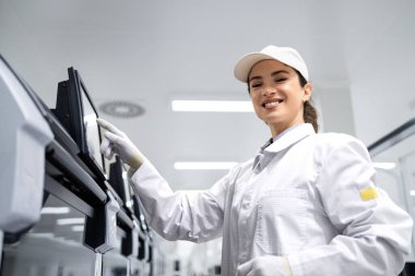 Fabrika içinde modern endüstriyel makine işleten kadın üretim hattı işçisinin portresi.