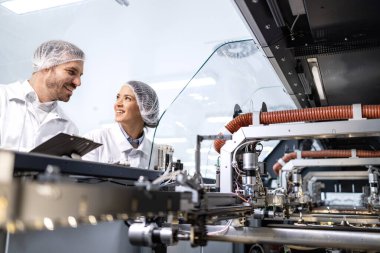 Bakım mühendisleri yüksek teknoloji fabrikasında duruyor ve endüstriyel makinelere hizmet veriyorlar..