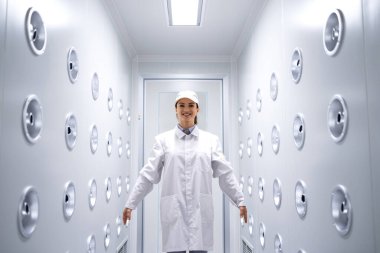 Fabrika işçisi endüstriyel hava üfleme tünelinde duruyor. Üretim hattına girmeden önce toz ve parçacıkları temizliyor..