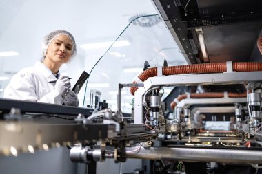 Yeni nesil endüstriyel makinenin üretim sürecini kontrol eden kadın fabrika mühendisi.