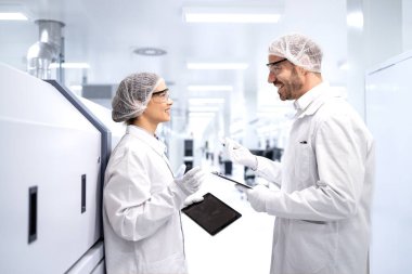 Fabrika işçileri birbirlerine danışıyor ve elektronik üretim fabrikasında fikirlerini paylaşıyorlar..