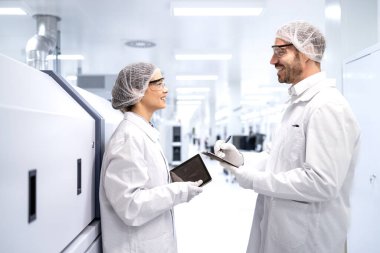 Fabrika çalışanları üretim makinesinin yanında durup tartışıyorlar..