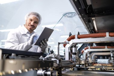 Fabrika bakım mühendisi yeni nesil endüstriyel makinedeki üretim sürecini izliyor.