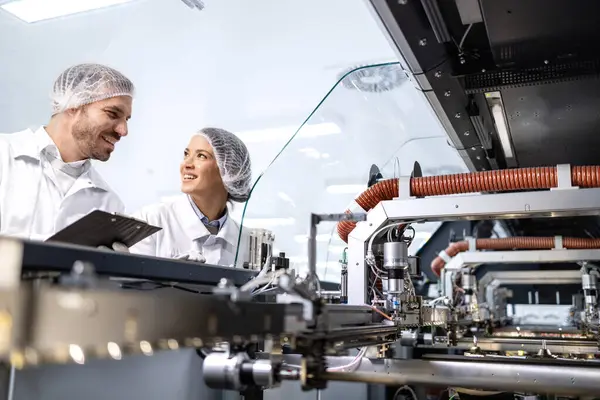 Bakım mühendisleri yüksek teknoloji fabrikasında duruyor ve endüstriyel makinelere hizmet veriyorlar..