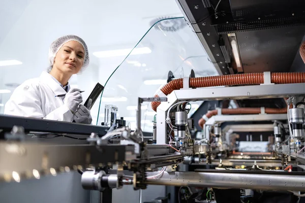 Yeni nesil endüstriyel makinenin üretim sürecini kontrol eden kadın fabrika mühendisi.