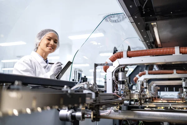 Kadın fabrika mühendisi yeni nesil endüstriyel makinede üretim sürecini izliyor..