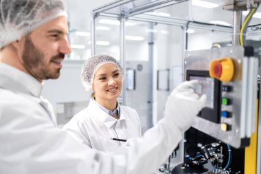 Deneyimli fabrika işçileri modern endüstriyel makinelerin üretim sürecini kontrol ediyor ve izliyorlar.