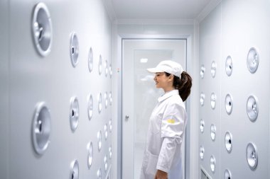 Fabrika işçisi endüstriyel hava üfleme tünelinde duruyor. Üretim hattına girmeden önce toz ve parçacıkları temizliyor..