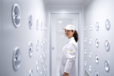 Fabrika işçisi endüstriyel hava üfleme tünelinde duruyor. Üretim hattına girmeden önce toz ve parçacıkları temizliyor..