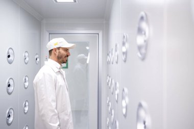 Fabrika işçisi endüstriyel hava üfleme tünelinde duruyor. Üretim hattına girmeden önce toz ve parçacıkları temizliyor..