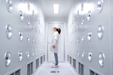 Fabrika işçisi endüstriyel hava üfleme tünelinde duruyor. Üretim hattına girmeden önce toz ve parçacıkları temizliyor..