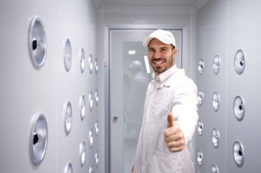 Fabrika işçisi endüstriyel hava üfleme tünelinde duruyor. Üretim hattına girmeden önce toz ve parçacıkları temizliyor..