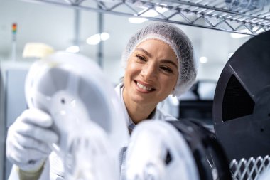 Kadın çalışan otomotiv endüstrisindeki elektronik parçaların envanterini kontrol ediyor.