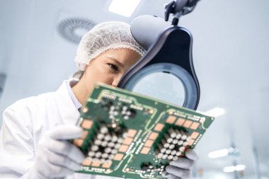 Deneyimli kadın mühendis, fabrikadaki elektronik parçaların kalitesini kontrol ediyor..
