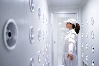 Fabrika işçisi endüstriyel hava üfleme tünelinde duruyor. Üretim hattına girmeden önce toz ve parçacıkları temizliyor..