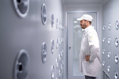 Fabrika işçisi endüstriyel hava üfleme tünelinde duruyor. Üretim hattına girmeden önce toz ve parçacıkları temizliyor..