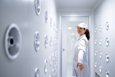 Fabrika işçisi endüstriyel hava üfleme tünelinde duruyor. Üretim hattına girmeden önce toz ve parçacıkları temizliyor..