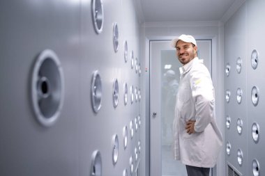 Fabrika işçisi endüstriyel hava üfleme tünelinde duruyor. Üretim hattına girmeden önce toz ve parçacıkları temizliyor..