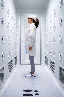 Fabrika işçisi endüstriyel hava üfleme tünelinde duruyor. Üretim hattına girmeden önce toz ve parçacıkları temizliyor..