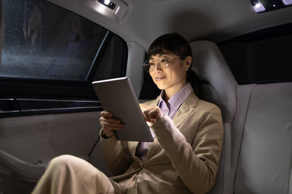 Female business person traveling in luxurious limousine and having important video call.