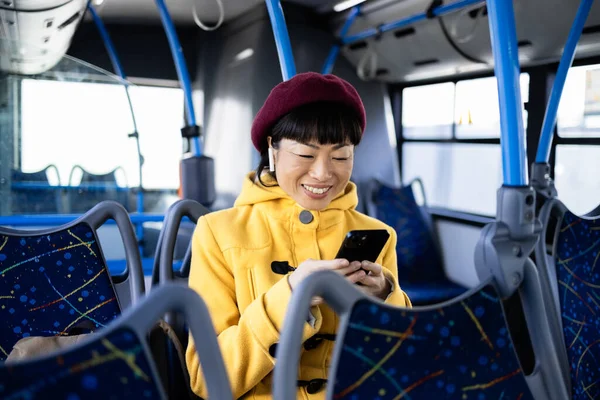 Woman traveling by public bus and texting message on the phone.