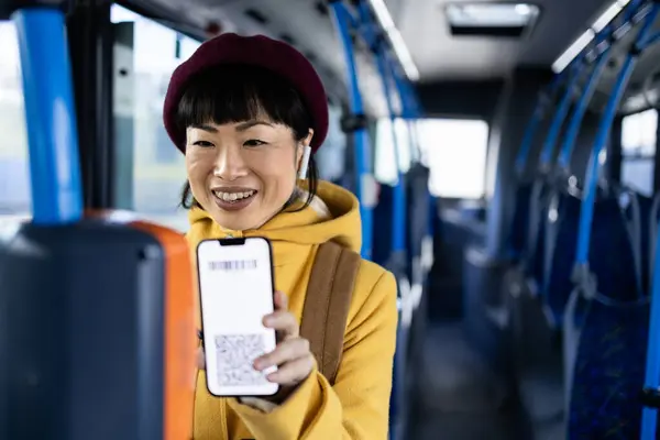 Female commuter validating ticket with smart phone app inside public bus transportation.