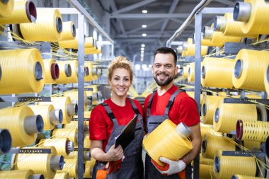 İp makaralı fabrika işçilerinin portresi endüstriyel örgü makinesinin yanında duruyor..